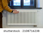 Small photo of Cropped photo of woman warming hands near radiator at home after walking in cold winter weather, female touching barely warm battery during heating season, person near window checking heating system