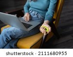 Small photo of Preventing carpal tunnel syndrome. Cropped photo of woman working on laptop doing daily exercises with expander or hand grip ring to help improve overall grip strength in your hand, selective focus