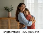 Small photo of Young loving mother hugging cuddling with teen girl daughter at home and smiling at camera, expressing unconditional love. Mother-daughter friendship, happy motherhood, parenting of adolescent