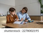 Small photo of Upset stressed child boy feeling frustrated while doing homework with mom at home. Kid sitting at kitchen table with teacher tutor having difficulties in learning. Problems with homeschooling