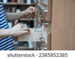 Small photo of Hands picking cards in library catalogue. Archive filing cabinet with drawers used for convenient quick search for cards with marks of books, magazines, scientific journals, dossier, documents