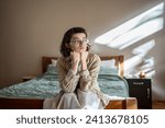 Small photo of Depressed lonely woman sitting on cozy bed sadly look at window feeling anxiety. Alone girl suffering from emotional pain having life troubles, problems. Mental disorder anhedonia, stress discomfort
