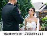 Small photo of Wedding ceremony. Bride and groom swear an oath each other on wedding arch background, newlyweds couple in love.