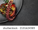 Small photo of Sea delicacy grilled octopus with grilled vegetables. Dishes on a dark decorated background