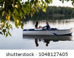 beautiful young wedding couple,bride with flower and her groom just married on small boat at pond with evening sun.happy loving couple rowing a small boat on a lake.