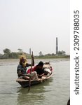 Small photo of Barisal, Bangladesh, March 12, 2023, Rural old sailor on a small wooden boat. Old sailor with a woman on a small dinghy floating on a river. Poor sailor and a girl on the river with fishing nets.