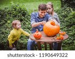Happy halloween. Father and two daughter carving pumpkin for Halloween outside. Happy family