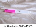 A negative pregnancy test kit on a white satin background