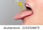 Small photo of tongue oil pipette. herbal alternative medicine and dietary supplements woman taking cbd hemp oil drops in mouth from dropper. medical cannabis oil. Supplement and alternative medicine concept