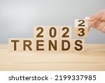 2023 trend concept. Hand flip wooden cube change year 2022 to 2023. gray background, copy space. 2022 trends concept. Hand flip wooden cube change on desk
