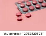 Pink tablets pill on blur blister pack of tablets pills on pink background. Prescription drugs. Woman health concept. Pharmaceutical industry. Online pharmacy banner. Drugs packaging. Treatment dose.