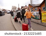 Small photo of Medyka, Poland - March 4, 2022: A line of Ukrainian women refugees fleeing the Russian invasion walk through a reception area just across the border.