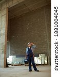 Small photo of Vertical wangle view of female construction worker wearing hardhat while standing in big concrete archway, copy space