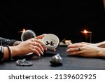 Small photo of Side view close up of female fortune teller reading coffee grounds telling destiny in seance with young woman in dark