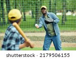 African man catching ball with glove throwing by his son during baseball game outdoors