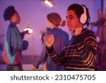 Waist up portrait of ethnic young man dancing with headphones on while enjoying silent disco party in neon light, copy space