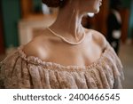 Small photo of Closeup of young woman wearing ballgown with focus on elegant neckline with pearl beads, copy space