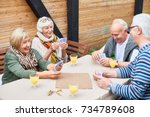Portrait of cheerful seniors playing card game at lunch table on outdoor terrace  laughing happily