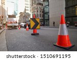 Red and white witches hat cone traffic warning sign barrier applying on busy street downtown on pedestrian footpath, road under construction defocused traffic controller Sydney city CBD, Australia 