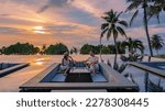 Small photo of couple watching the sunset in an infinity pool on a luxury vacation in Thailand, man and woman watching the sunset on the edge of a pool in Thailand on vacation