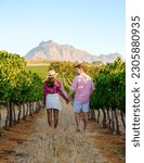 Small photo of Couple of men and women at a Vineyard landscape at sunset with mountains in Stellenbosch, near Cape Town, South Africa. wine grapes on the vine in the vineyard Western Cape South Africa