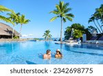 Small photo of Man and Woman relaxing in a swimming pool, a couple on a honeymoon vacation in Mauritius tanning in the pool with palm trees and sun beds