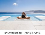 young woman in the swimming pool ,infinity pool relaxing looking out over the ocean caldera of Oia Santorini Greece