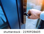 Male hand holding a handle of key free smart lock. Keyless access to home or hotel.