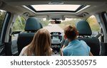 Small photo of Rear view. Children boy and girl sitting in back seat of car during family trip. Happy family is driving a modern car