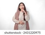 Portrait of Asian Muslim woman wearing headscarf veil placing hands on the stomach feeling hungry and want to eat while fasting, isolated over white background. Ramadan and Eid Mubarak concept
