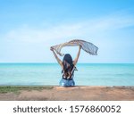 Small photo of Behind woman sit at the beach show scarf up with blue ocean blue sky beautiful beach landscape on holiday concept
