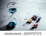Small photo of Hour glass on calendar with thumbtacks concept for time slipping away for important appointment date, schedule and deadline