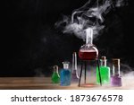 Small photo of Magic and wizardry concept. Magic potions on table. Potion with vapor streaming from bottle. Alchemy concept.