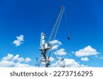 Small photo of Three different sized cargo cranes and slewing cranes with cabin in front of a blue sky, plenty of copy space
