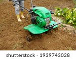 Small photo of Man working in the spring garden with tiller machine. with rototiller, tiller tractor, cutivator, miiling machine.