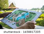paper sheet of layout plan with hands and garden background, that shown design of clubhouse landscape or garden design   drawing by hand with color marker pens and color pencil, selective focus