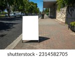 Small photo of Background texture of a blank white advertisement board on walkway. Mockup template of a standing easel on pedestrian sidewalk in an small Australian regional town.