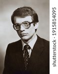 Small photo of Portrait of young Soviet guy with glasses, in jacket and tie. Vintage black and white paper photo, 1970s. Transferred property, family archive. Outdated quality