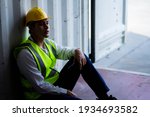 Factory worker man sit in the cargo container and lost job. Concept of good system and manager support for better industrial business.