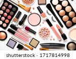 Decorative cosmetics and makeup brushes on a white background, top view