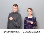 Studio shot of adult couple, disappointed man and serious focused woman are pointing at each other. Concept of relationship, interaction between people, gender relations, communication issues
