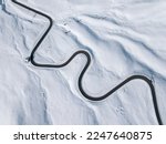 Aerial view of a winding road in the snow in Passo Giau, high alpine pass near Cortina d'Ampezzo, Dolomites, Italy. Winter nature background.