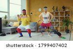 Small photo of Sports parody. Comical funny unfit retro looking young men training with resistance bands doing wrong exercises having fun home workout.