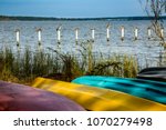 Ten brown pelicanons, each on their own post, with colorful canoes on the shore of Mobile Bay, at Fairhope Alabama