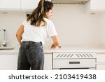 young woman cleaning the ceramic hob in kitchen