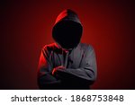 Silhouette af man without face in hood on a red background. Anonymous crime concept
