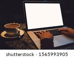 A cup of cappuccino coffee with laptop white screen on table. Royalty high quality free stock photo image of coffee cup with laptop for working in a coffee shop, typing with blank screen white color