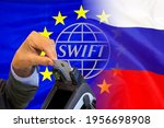 Flag of EU and Russia flag and text of SWIFT. Hand of woman with credit card in payment terminal.  Financial regulation sanctions concept