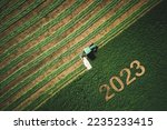 2023 Happy New year concept for agriculture, business, goals, success and new start banner. Industrial tractor on a green field.