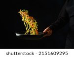 Italian pasta with greens and shrimps in a pan in a frozen flight on a black background. Sea food. Restaurant, hotel, banquet, home cooking. Healthy vegetarian food, healthy lifestyle.